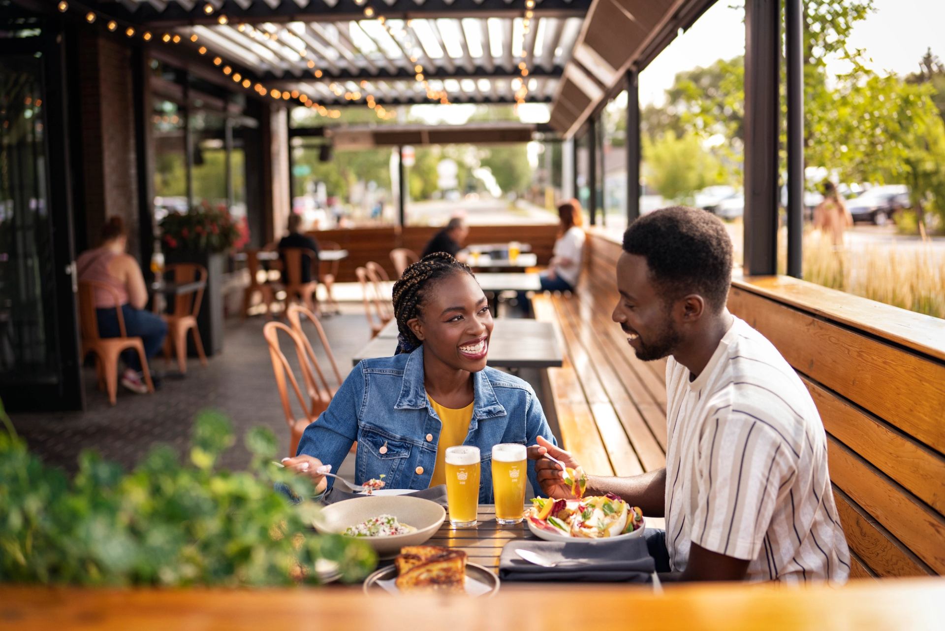 A couple has a meal and a beer on an outdoor patio.