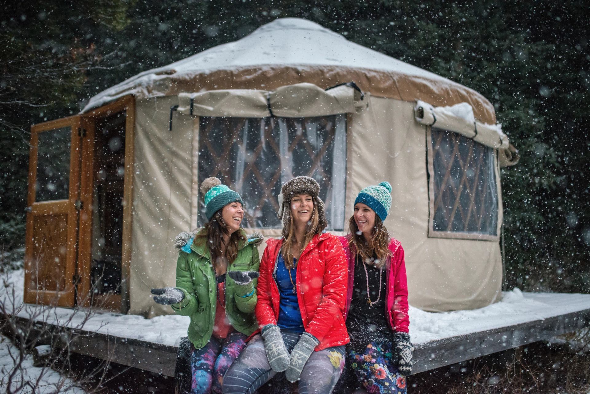 Women sit outside of a yurt at Mount Engadine Lodge while it snows