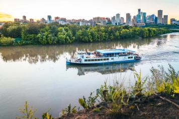 The Edmonton Riverboat floats down the river with the Edmonton cityscape in the background.