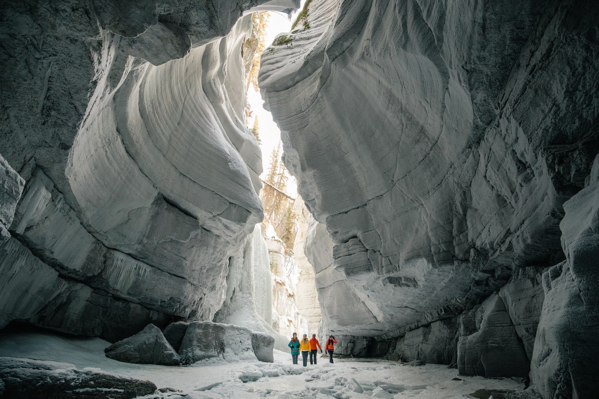 A distant shot of a group touring Maligne Canyon, surrounded by cool canyon formations, while ice walking in Jasper National Park