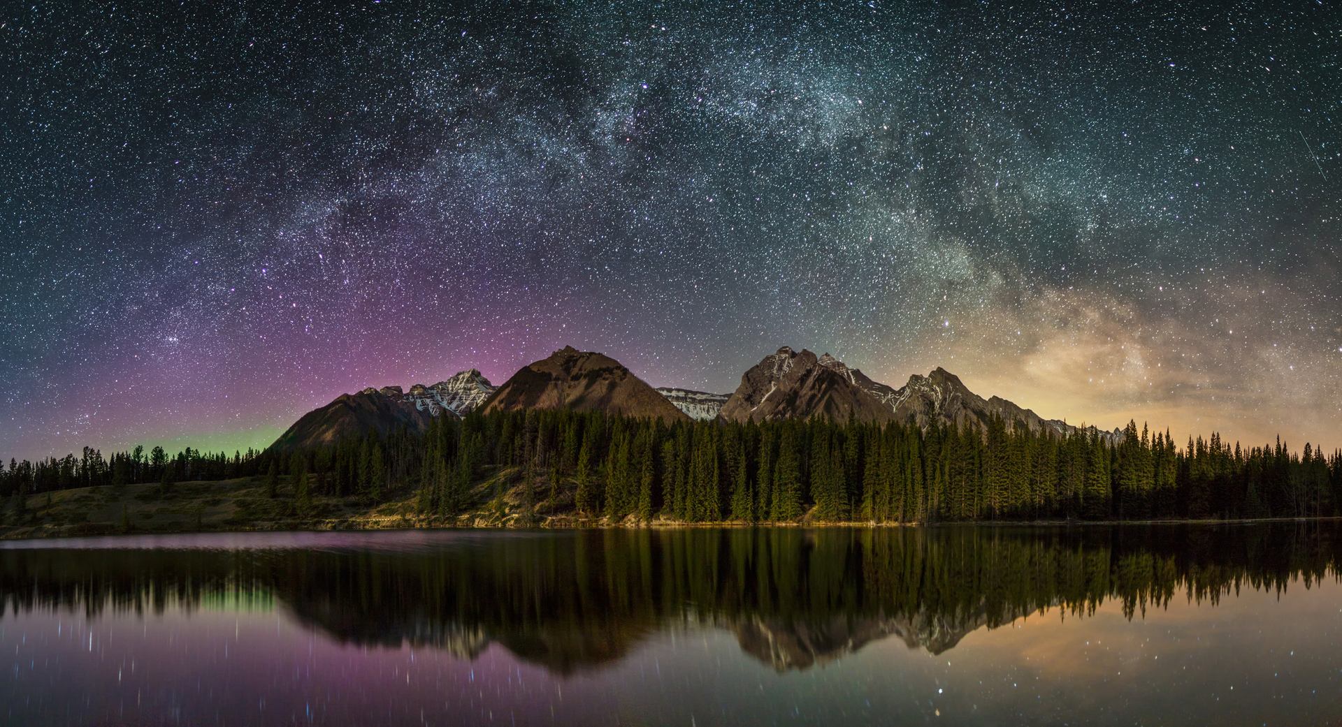 An image of the starry night sky over Johnson Lake in Banff National Park.