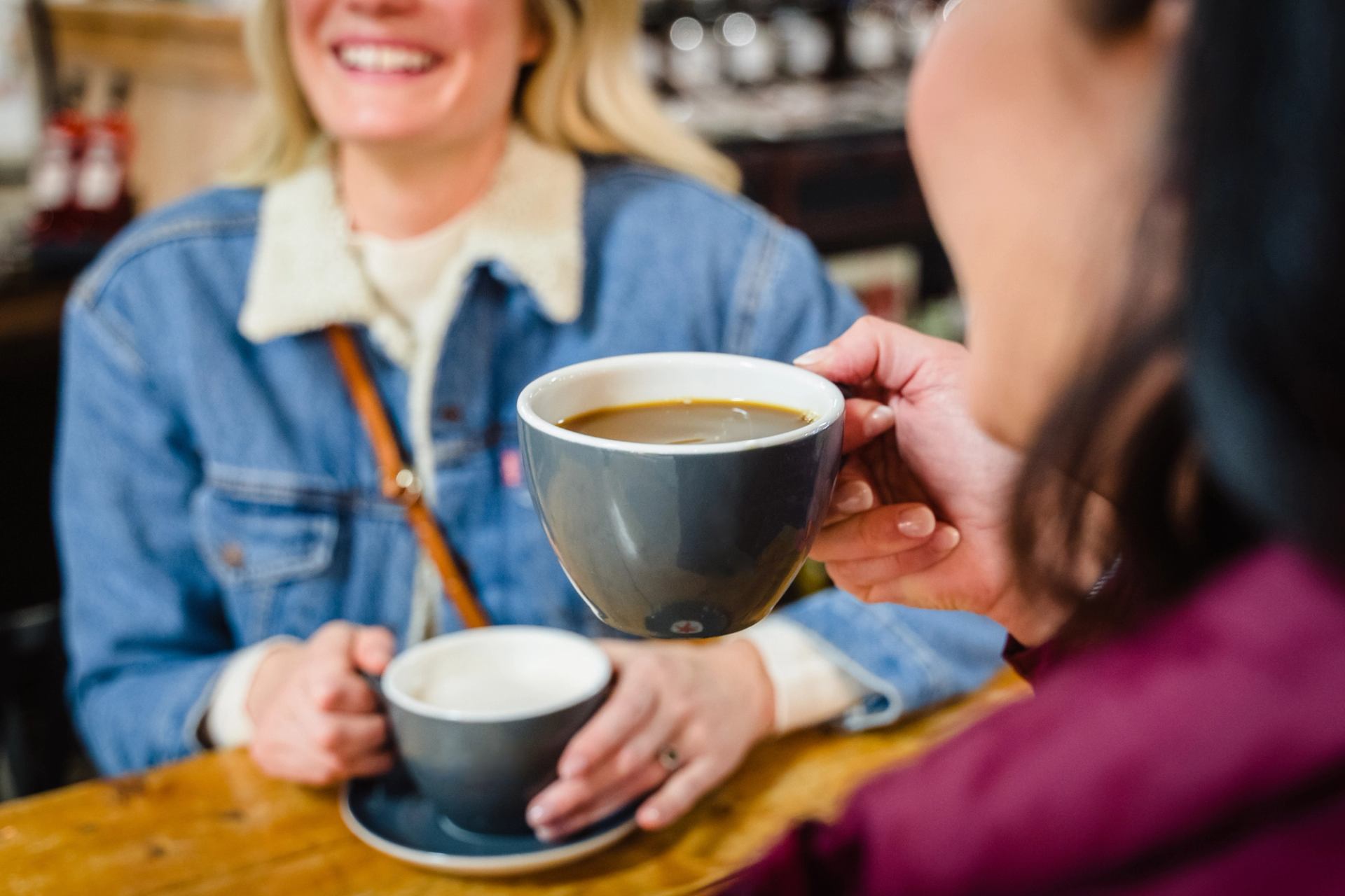 A close-up of friends enjoying coffee at a table.