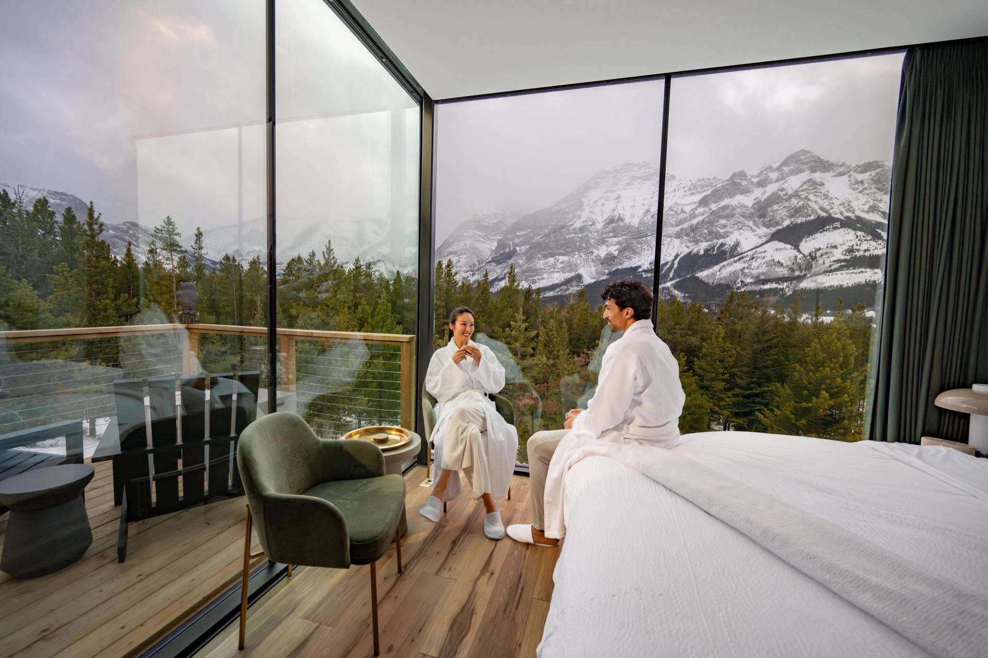 A couple sit next to full length windows at Skyridge Glamping in Kananaskis.