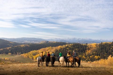 A group of people on a trail ride in the foothills.