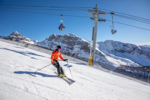 A skier carves down an intermediate run, under the chairlift, at Sunshine Village Ski & Snowboard Resort in Banff National Park.