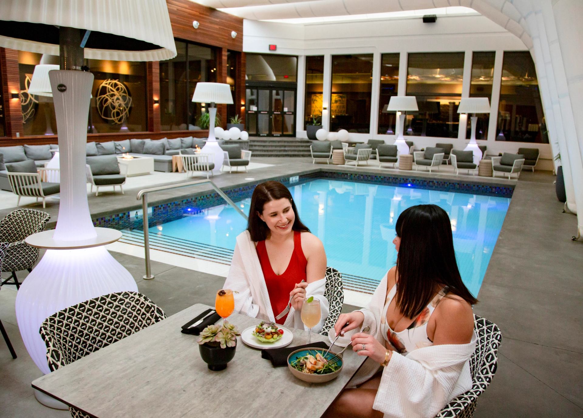 Two women eating lunch by the indoor pool at Hotel Arts.