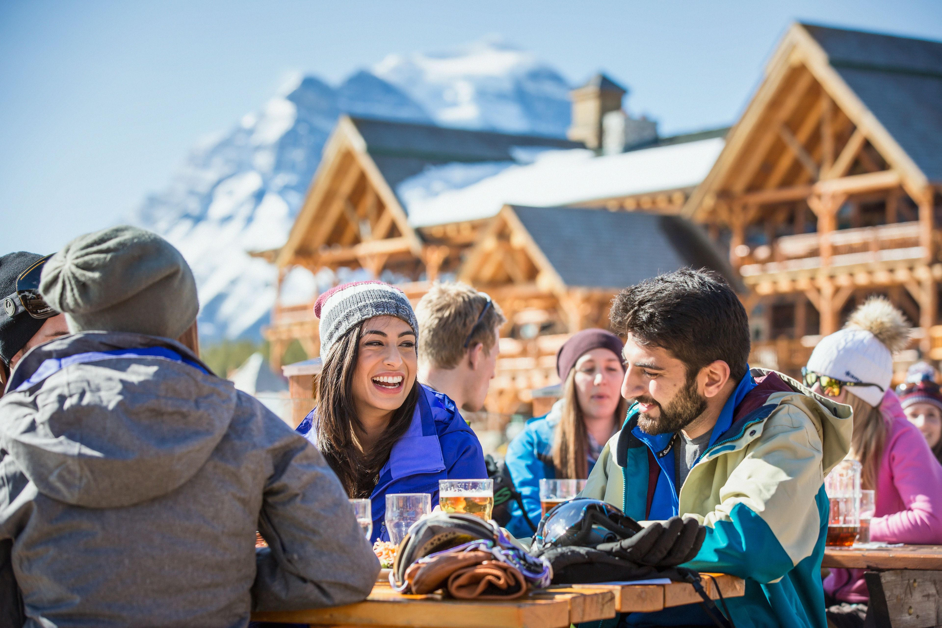 Friends enjoying food and drinks at an outdoor patio after a day of skiing at Lake Louise Ski Resort in Banff National Park