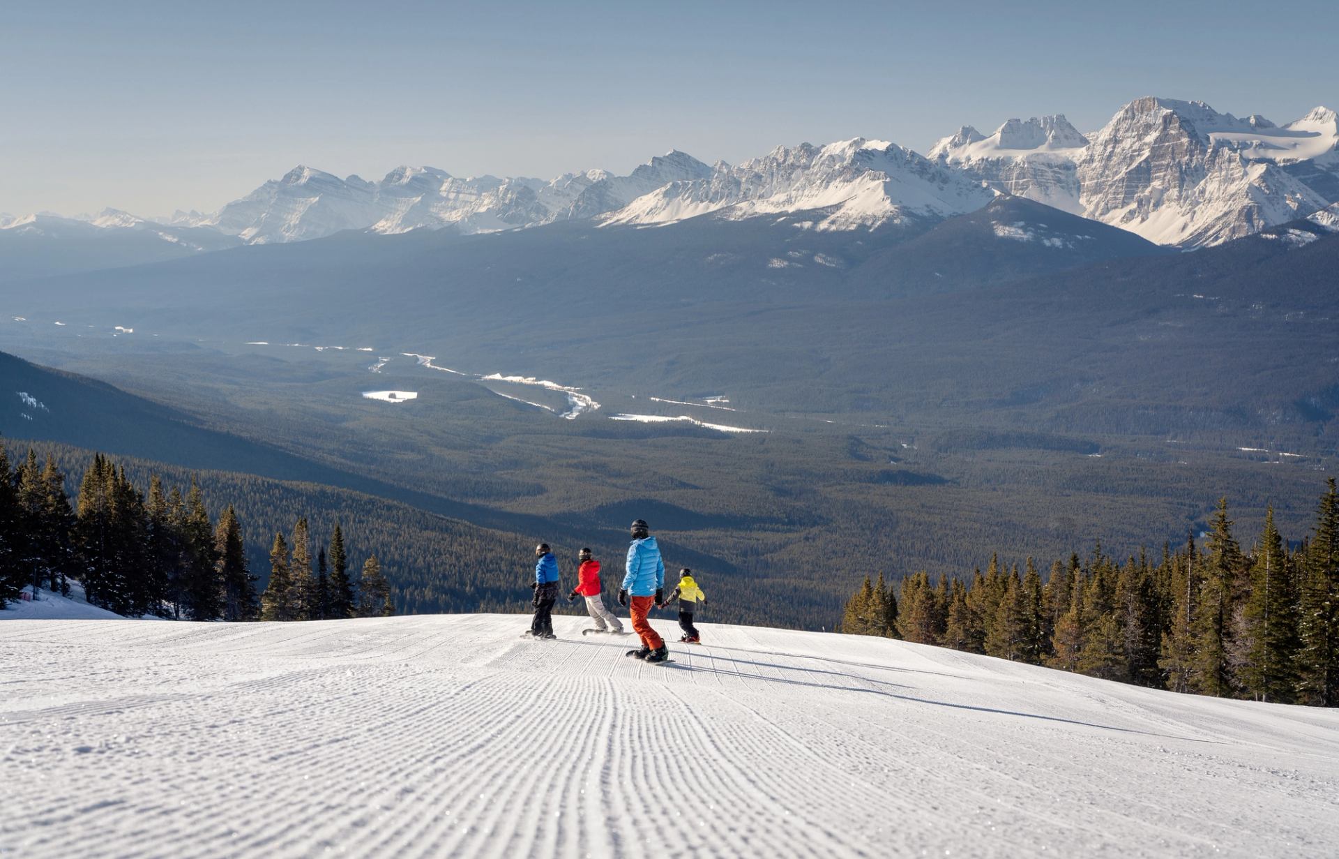 A group of four snowboarders carve at Lake Louise Ski Resort.