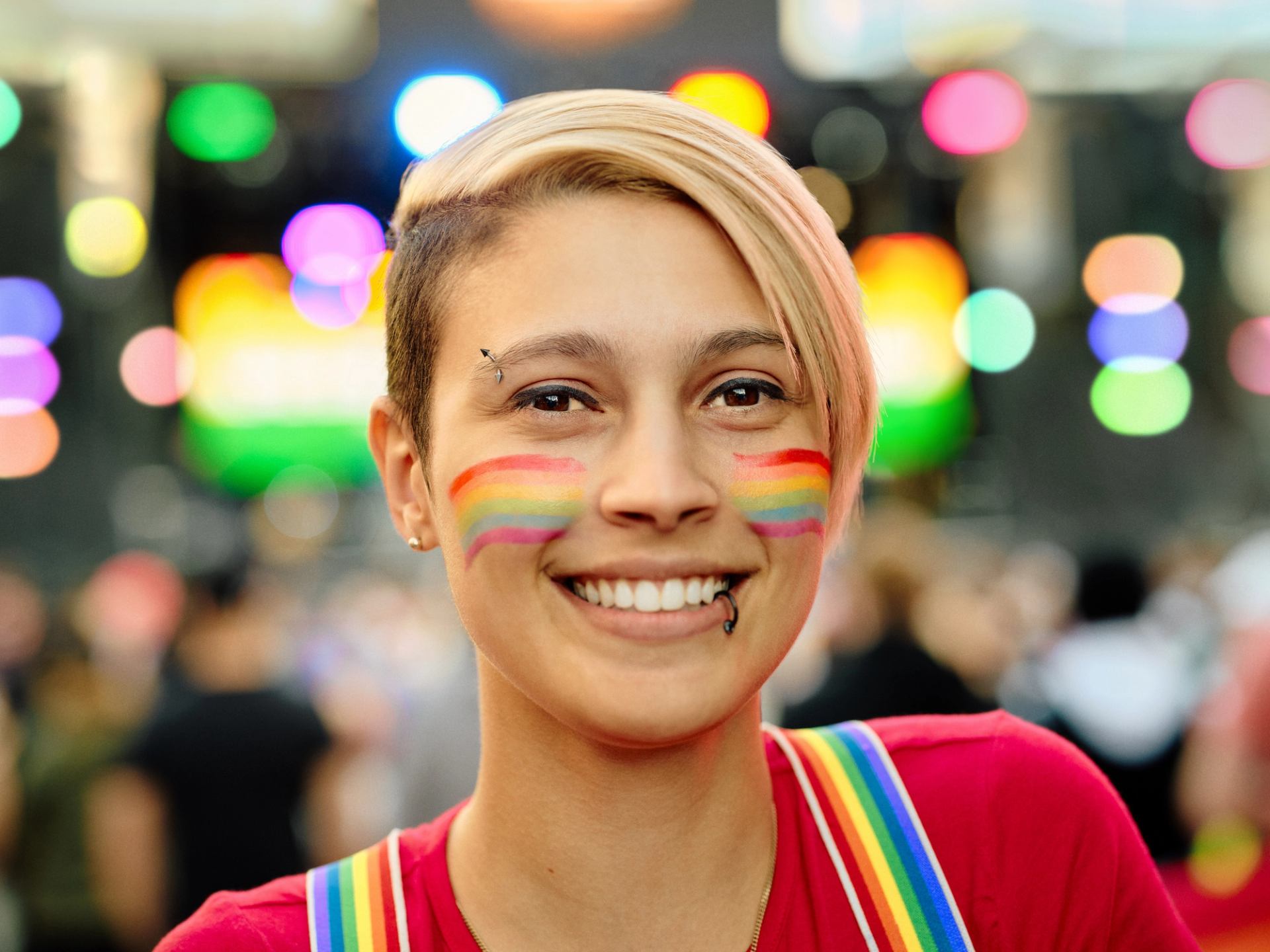A smiling attendee with a rainbow-painted face at the Edmonton Pride Festival.