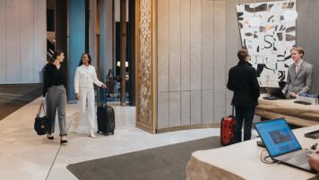 2 women near reception, and another guest and receptionist at JW Marriott Edmonton ICE District.