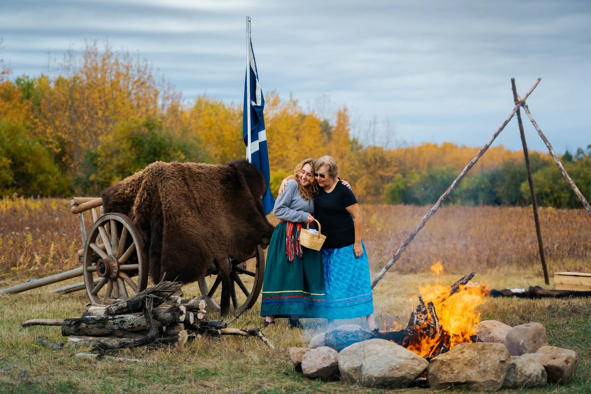 Women standing in front of a fire at Métis Crossing.