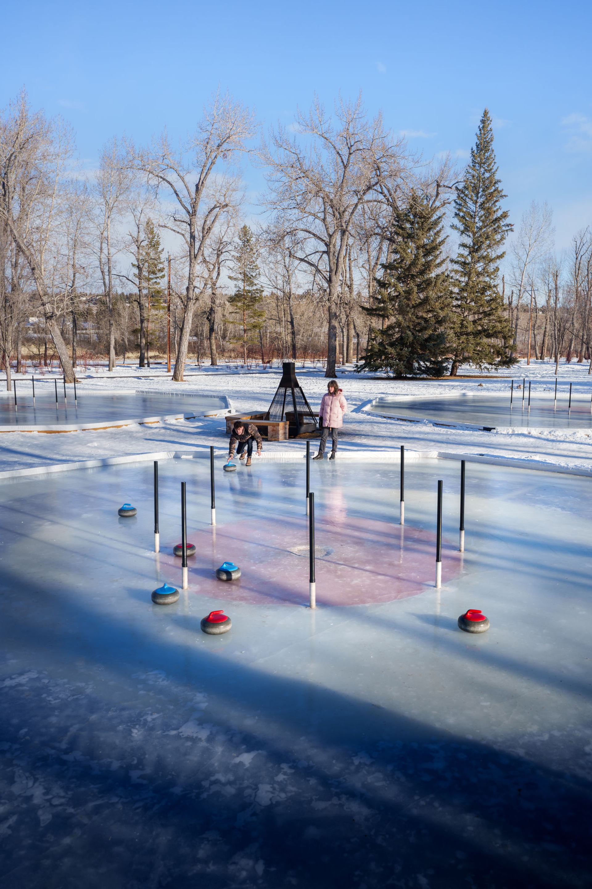 A young couple playing crokicurl at Bowness Park in Calgary on a sunny winter day.