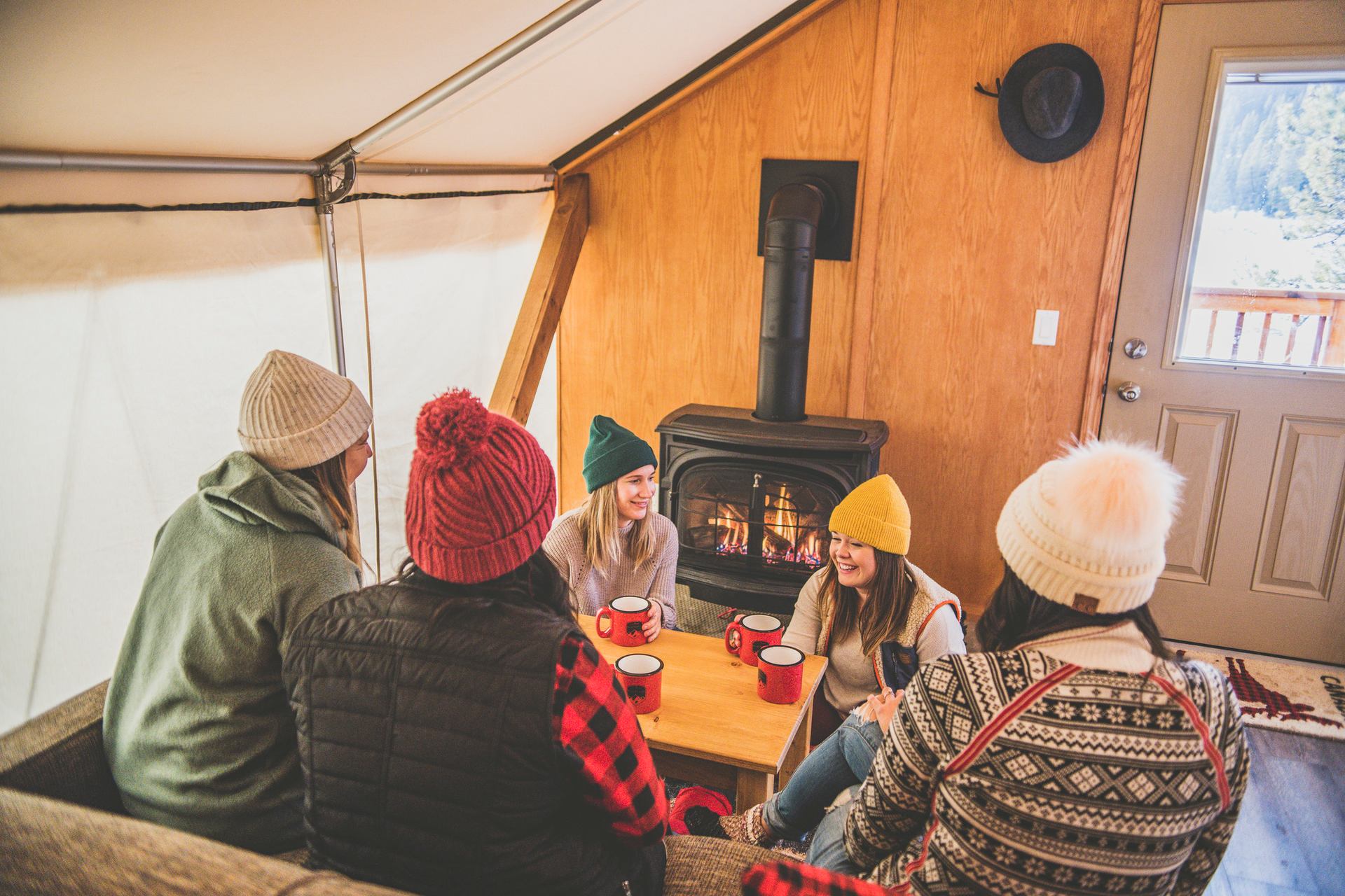 Friends socializing inside their winter glamping tent.