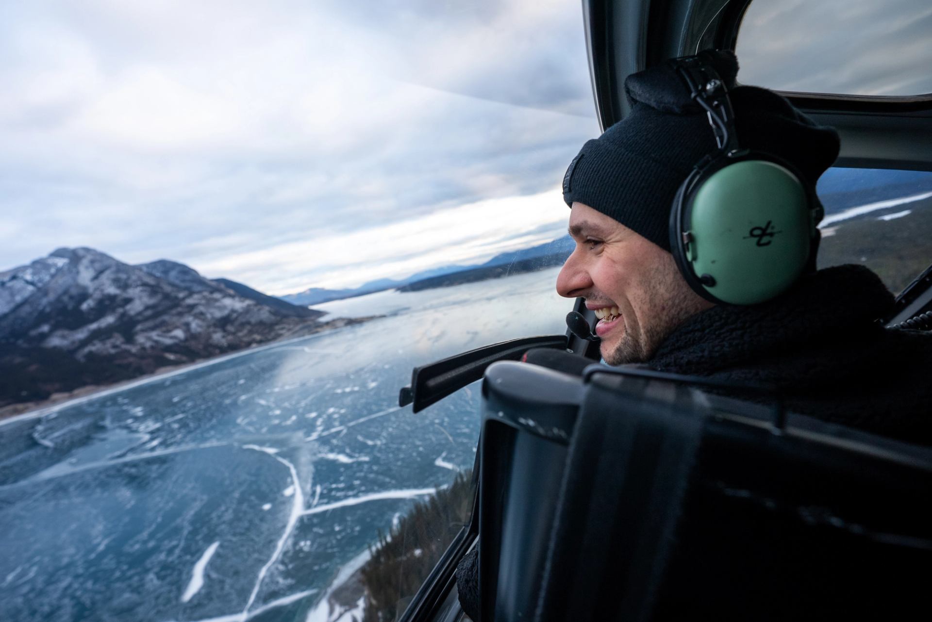 David Popa looks out a helicopter window onto Abraham Lake.
