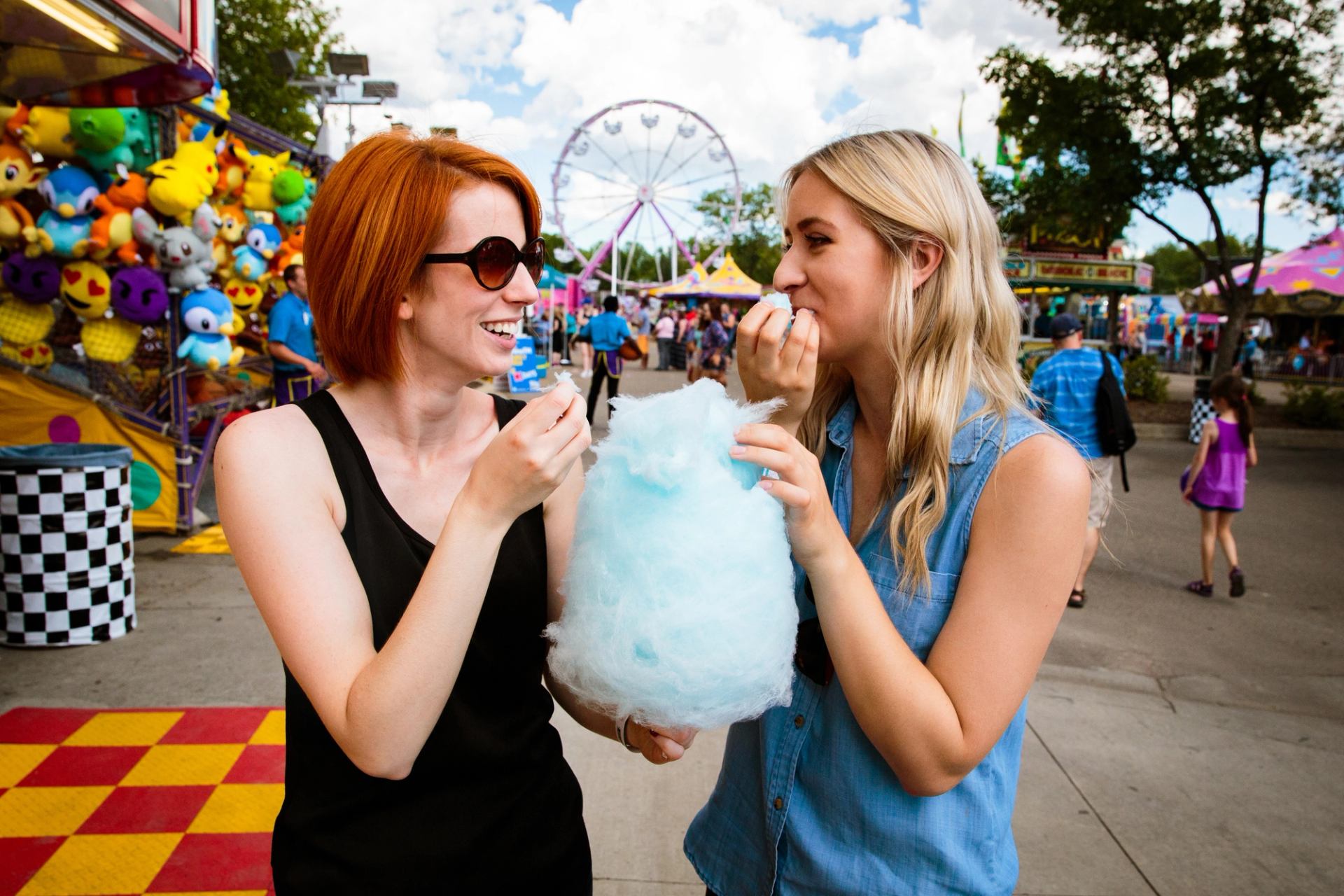 Women eating cotton candy at a midway