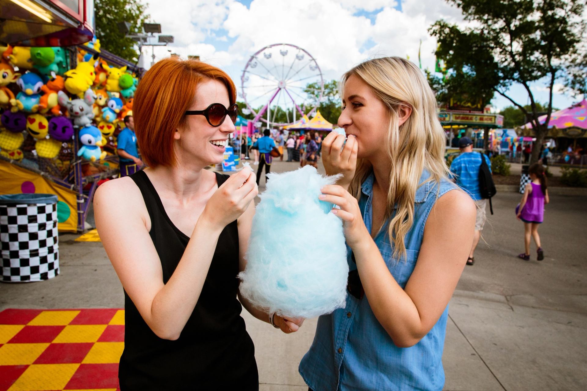 Women eating cotton candy at a midway