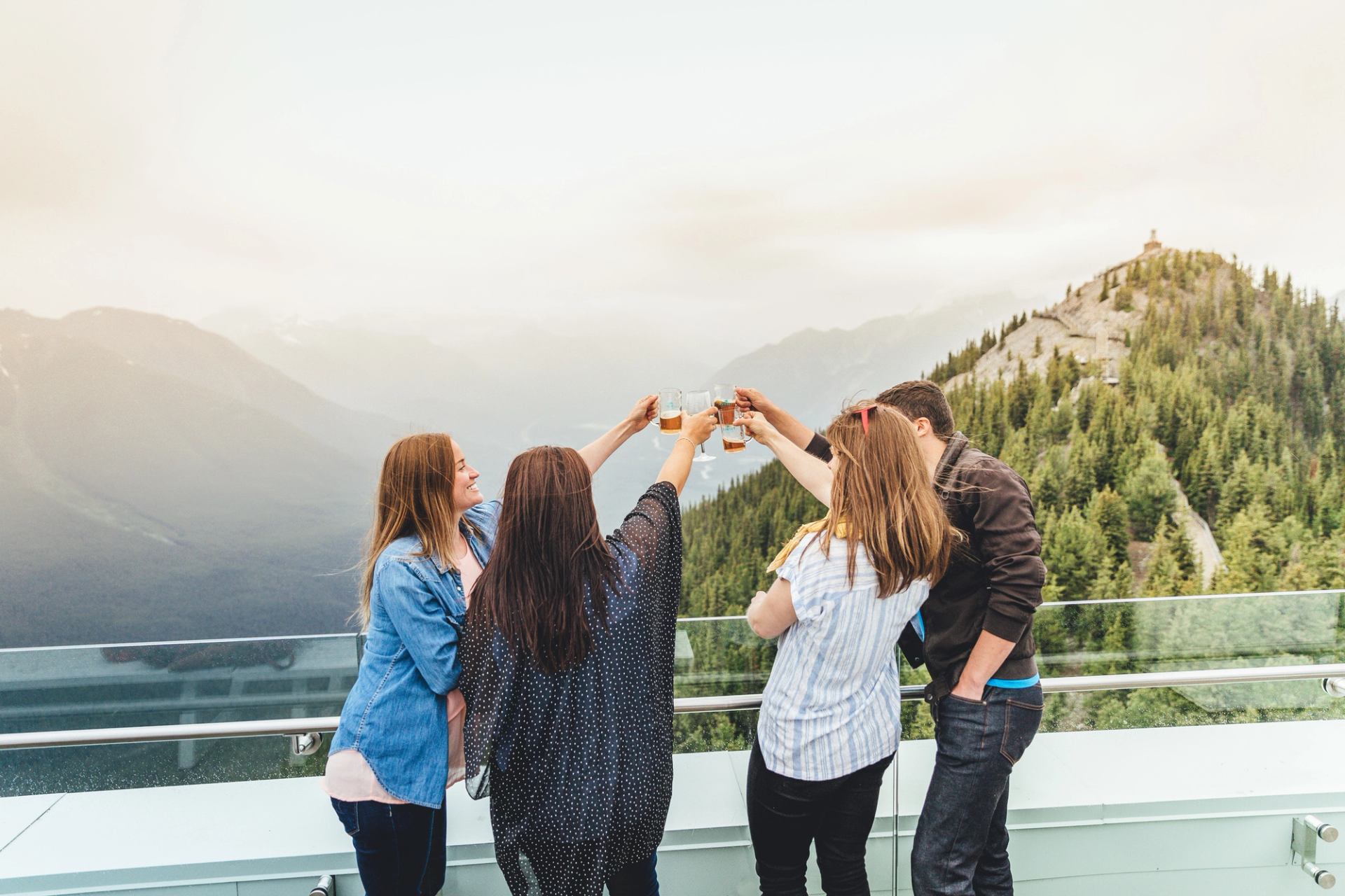 People enjoying beverages at the top of the Banff Gondola with moutain views during the evening