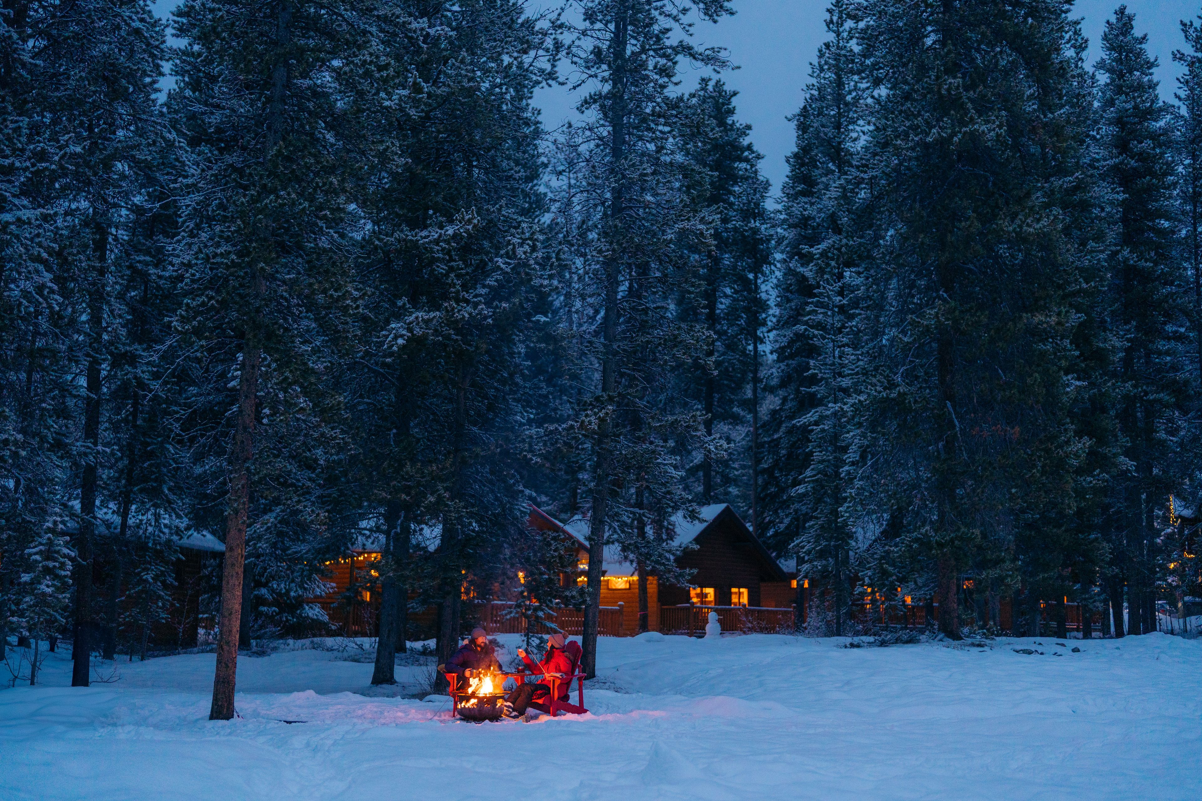 Couple sitting around campfire pit enjoying dessert at Baker Creek Cabins.