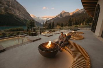 A couple in an outdoor pool look to the mountains.