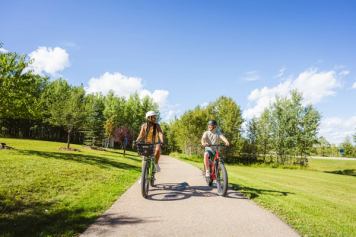 Two people riding bikes on a path near downtown Rocky Mountain House.