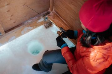 Shot of a women from above looking down at her ice fishing hole