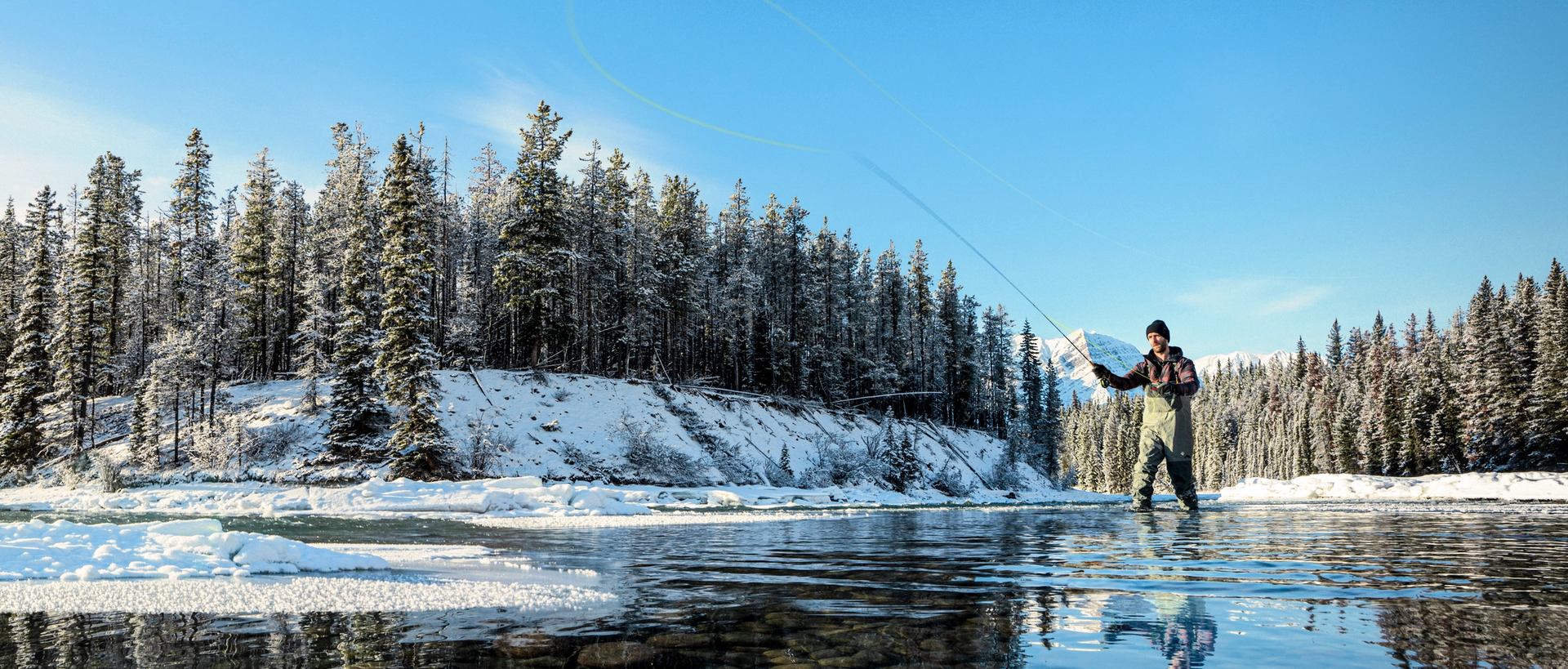 A person fly fishing in the Athabasca River in Jasper National Park.