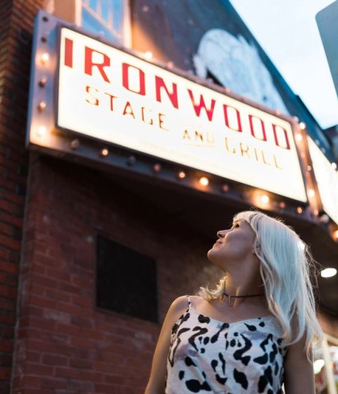 Woman standing under the sign at the Ironwood in Inglewood