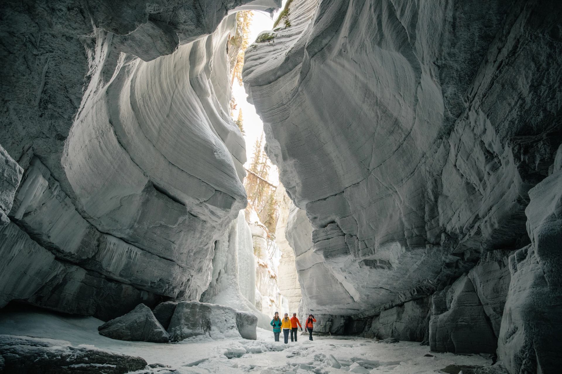 A group touring Maligne Canyon, surrounded by cool canyon formations, while ice walking and hiking in Jasper National Park.