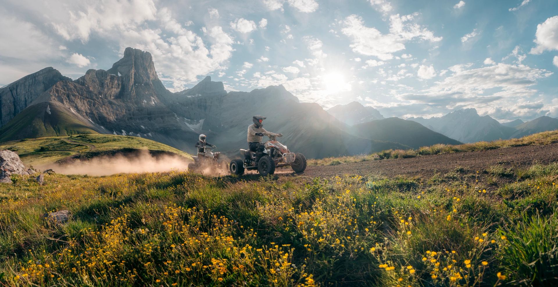 Two ATV Riders ride across a dirt trail on Fortress Mountain.