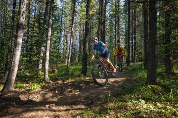 A single rider with guide mountain biking through trails with Outbound Elements.