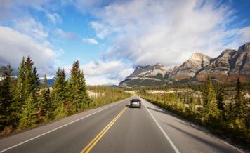 Vehicle driving down the Icefields Parkway with mountain views in Jasper National Park, Alberta.