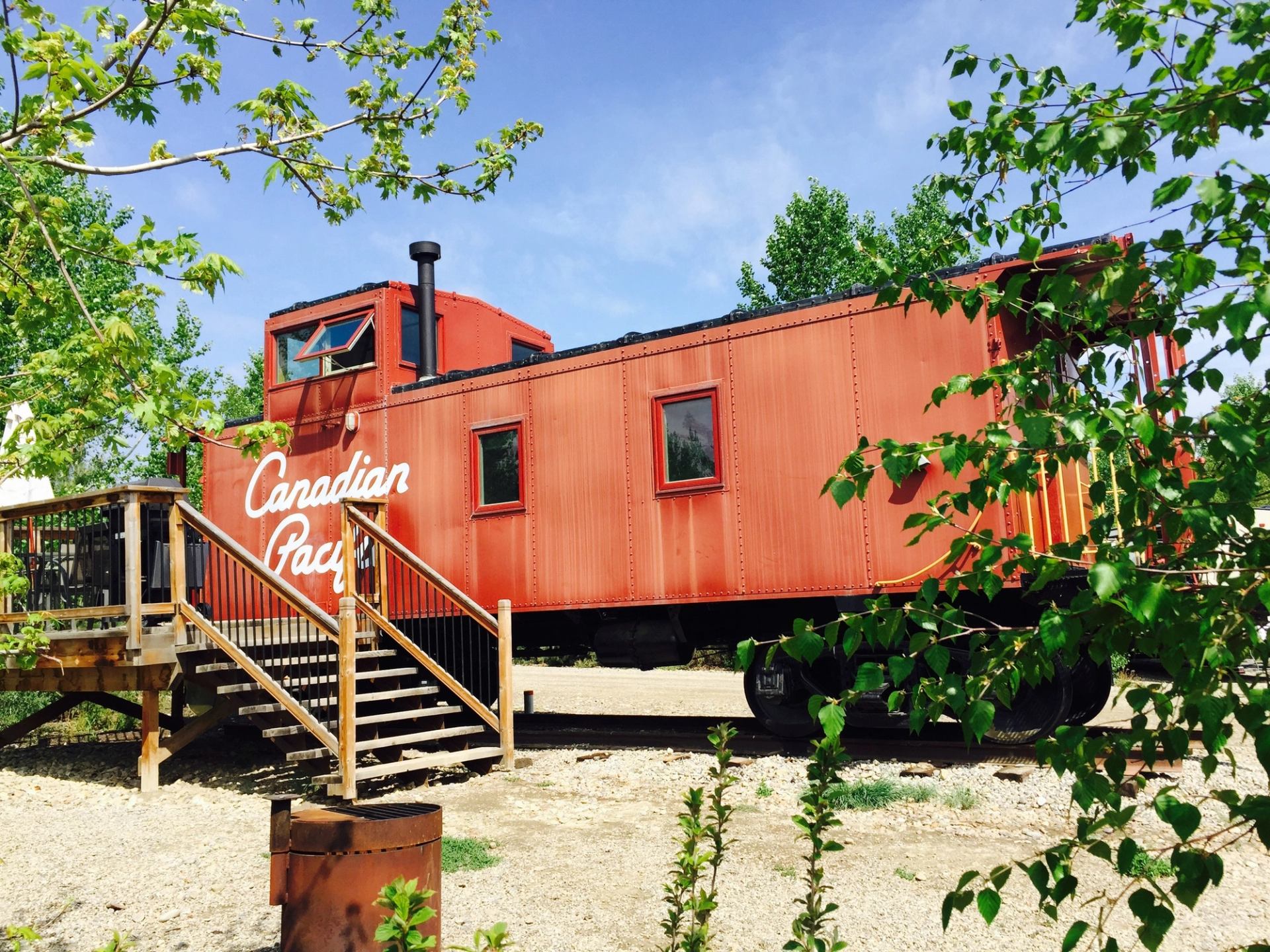 The exterior of a red cabin that used to be a train caboose that has Canadian Pacific written on it.