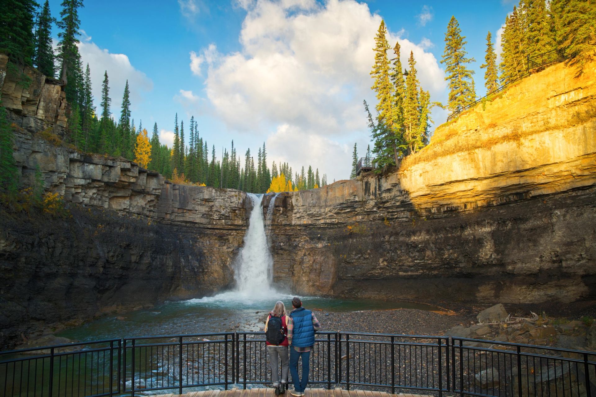 Couple enjoying a view of Crescent Falls from an observation platform as the sun dips into the canyon.