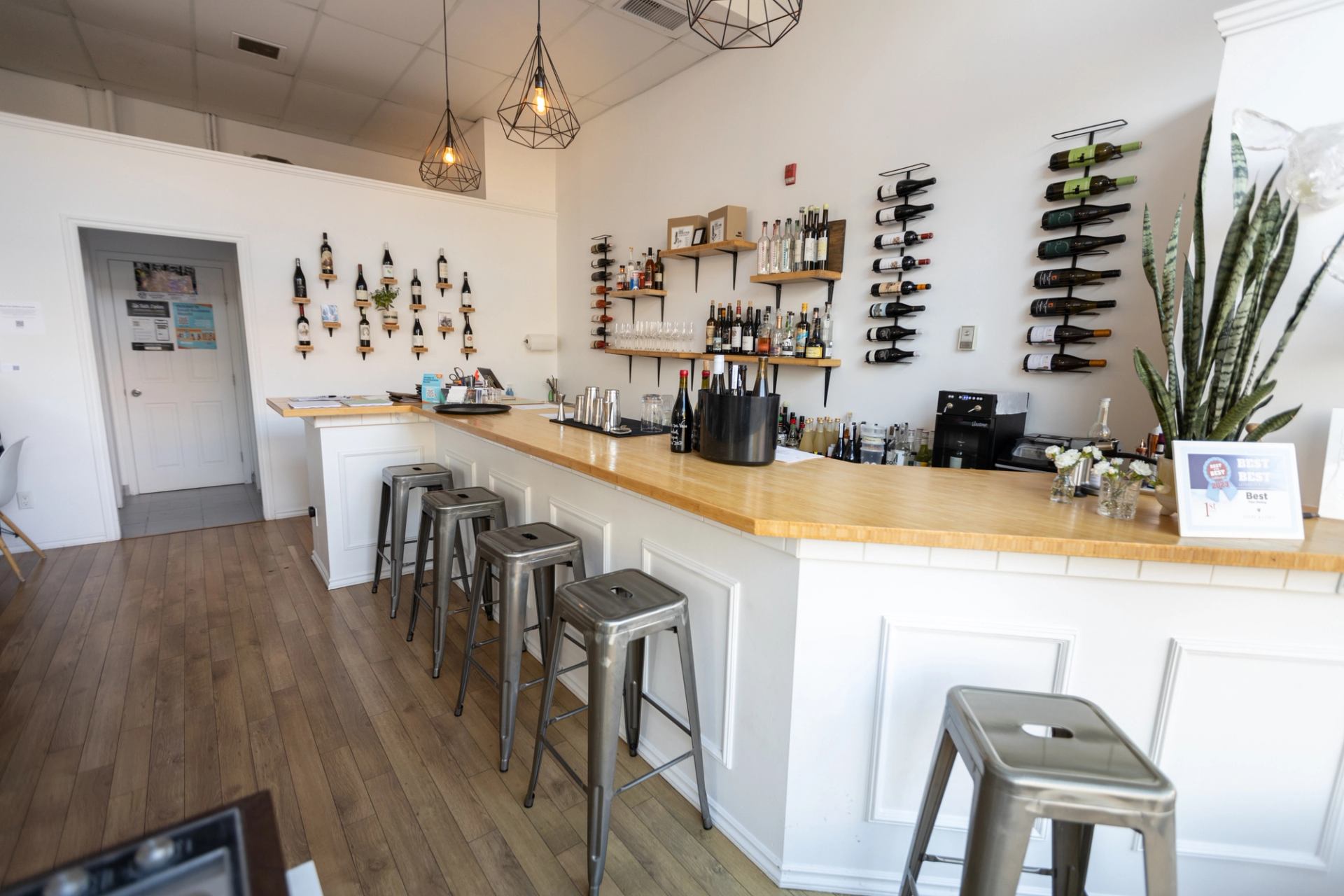The modern bar interior at Steel & Vines Wine Bistro in Lethbridge, with wine bottles hanging artfully on the wall.