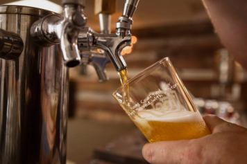 A pint of beer is poured from a draft tap in a brewery.