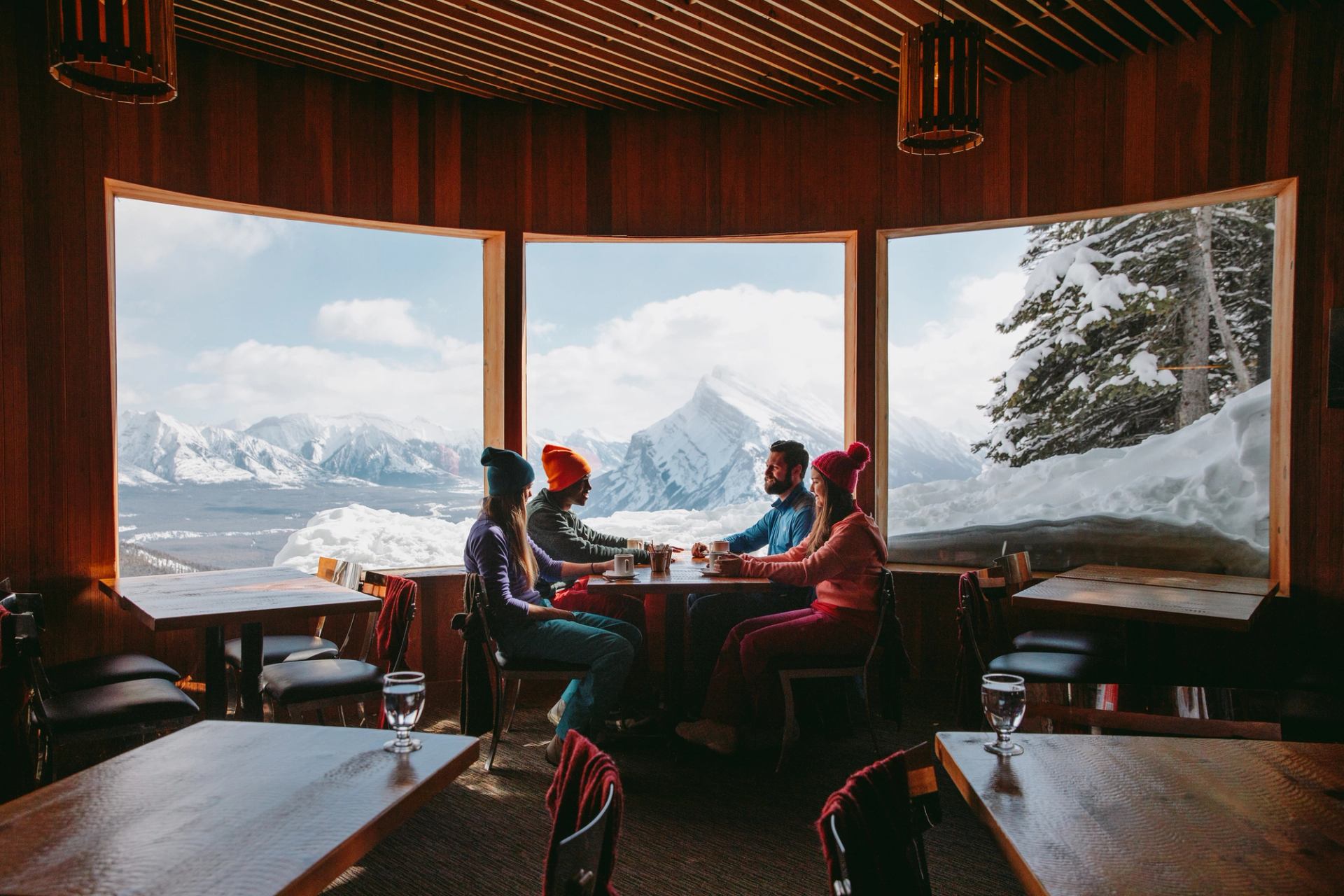 A group of four people relaxing and taking in the panoramic mountain views at Cliff House Bistro on Mt. Norquay in Banff.