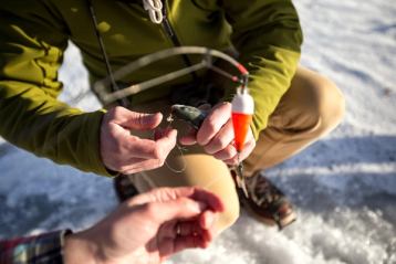 Close up of two people preparing a fishing rod to go ice fishing