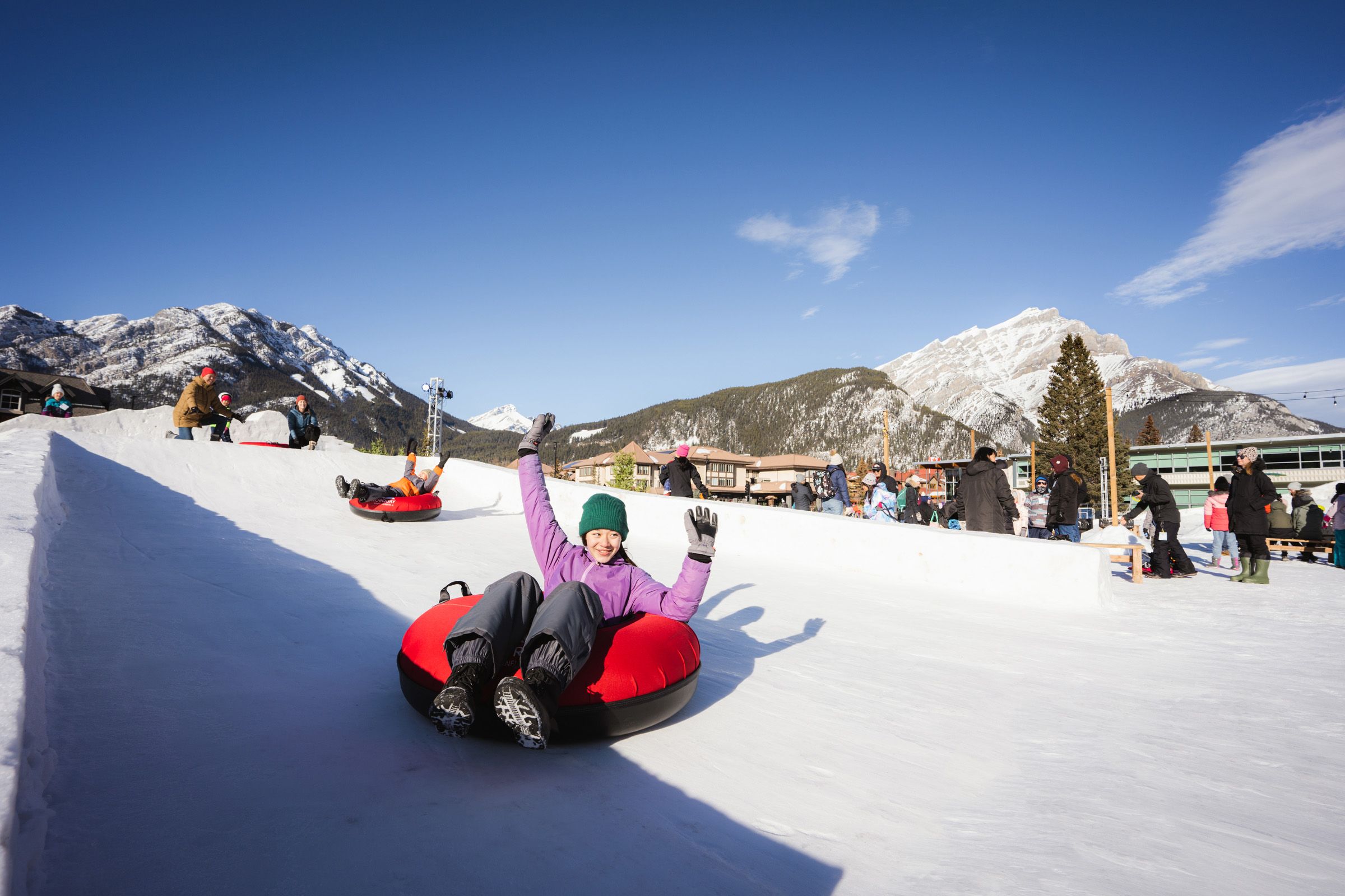 Riders tubing, hands in the air, while enjoying the SnowDays Festival in Banff.
