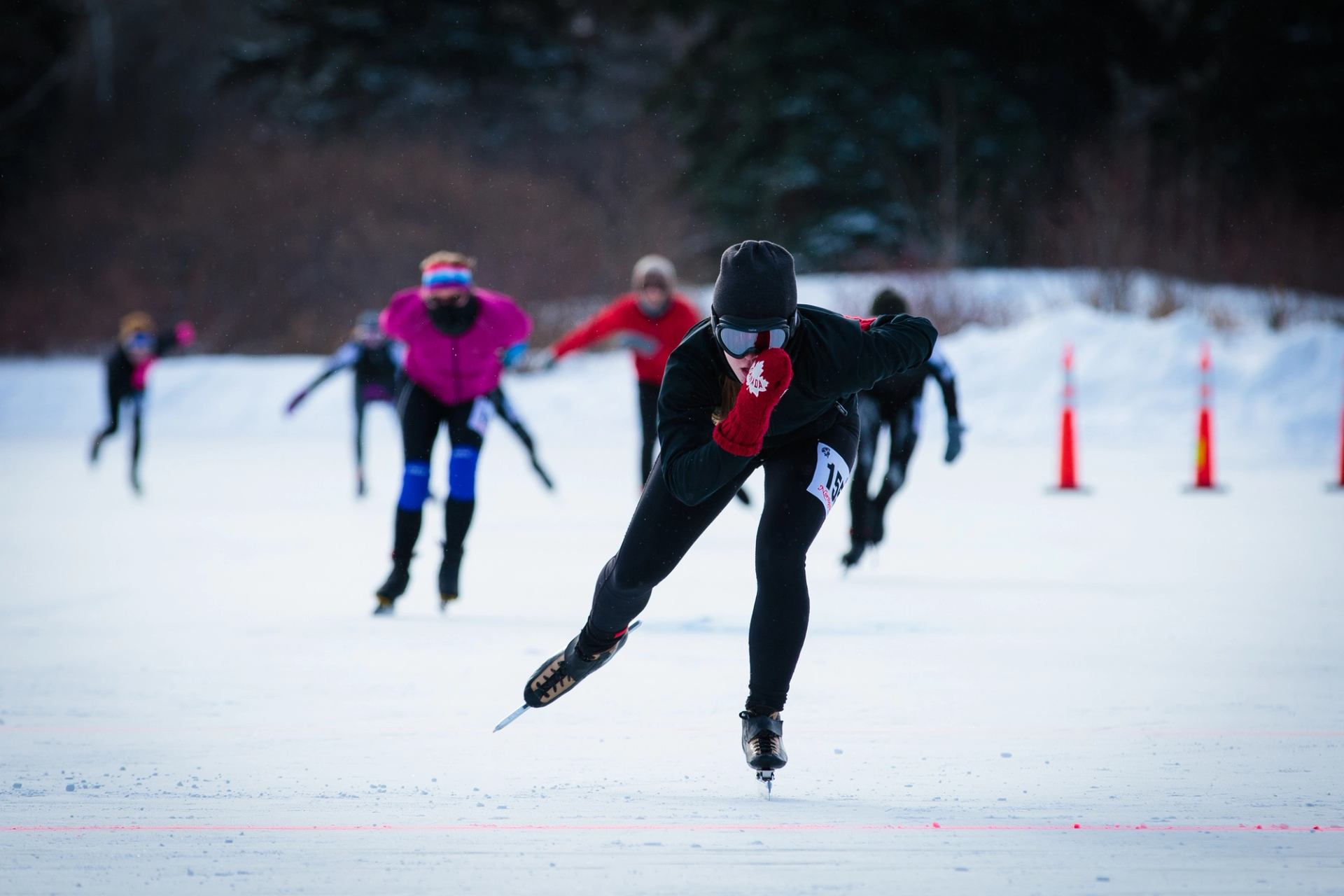 Speed skaters racing on an outdoor rink.