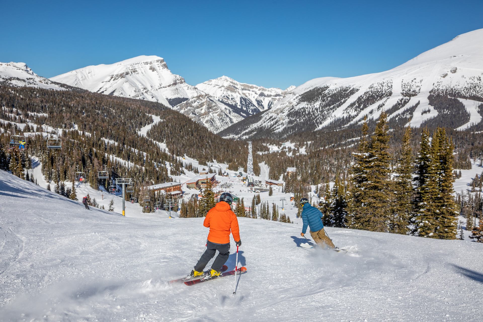 Two skiers ski down an intermediate run at Sunshine Village in Banff National Park.