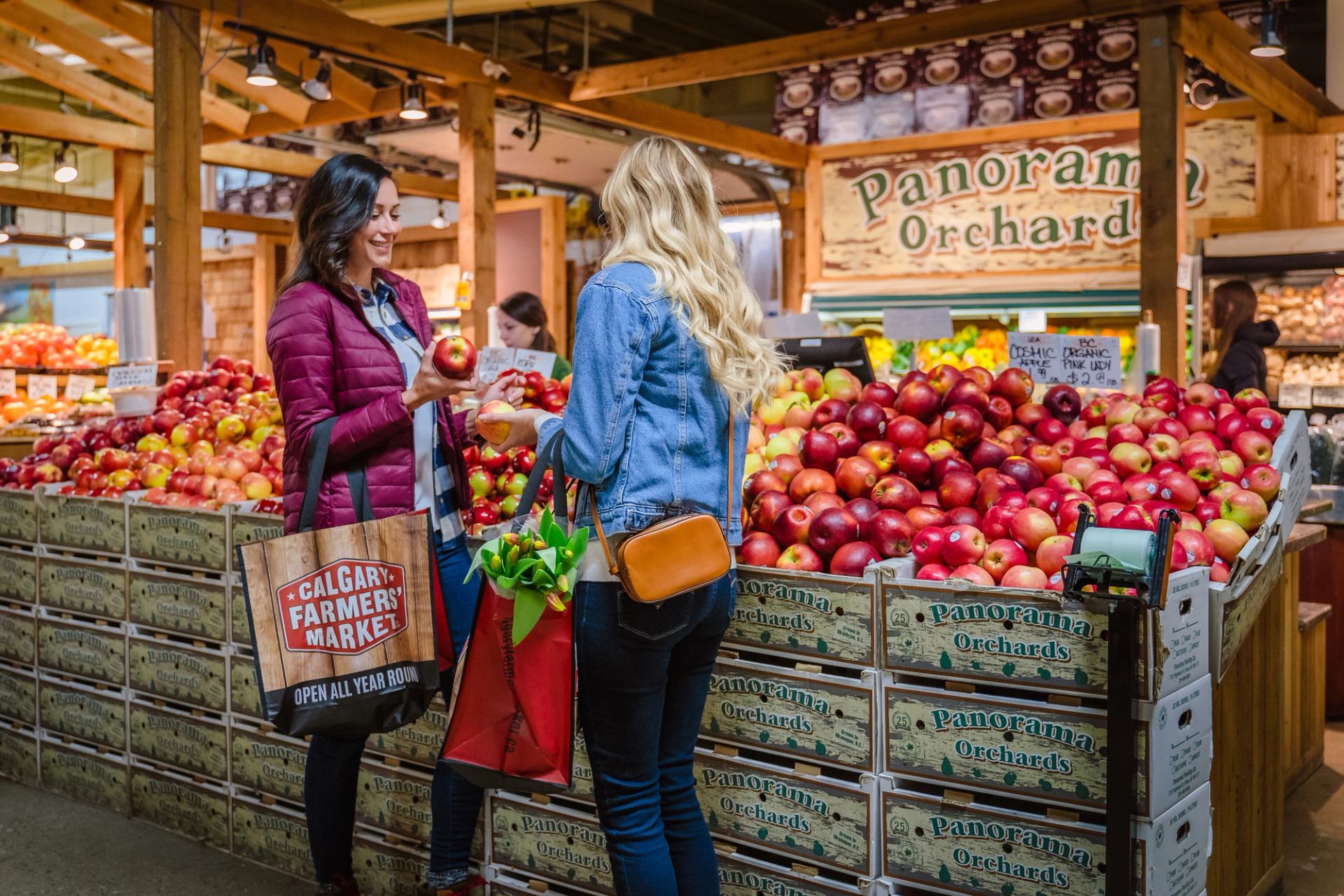 Two friends look at an apple display at the Calgary Farmers’ Market.