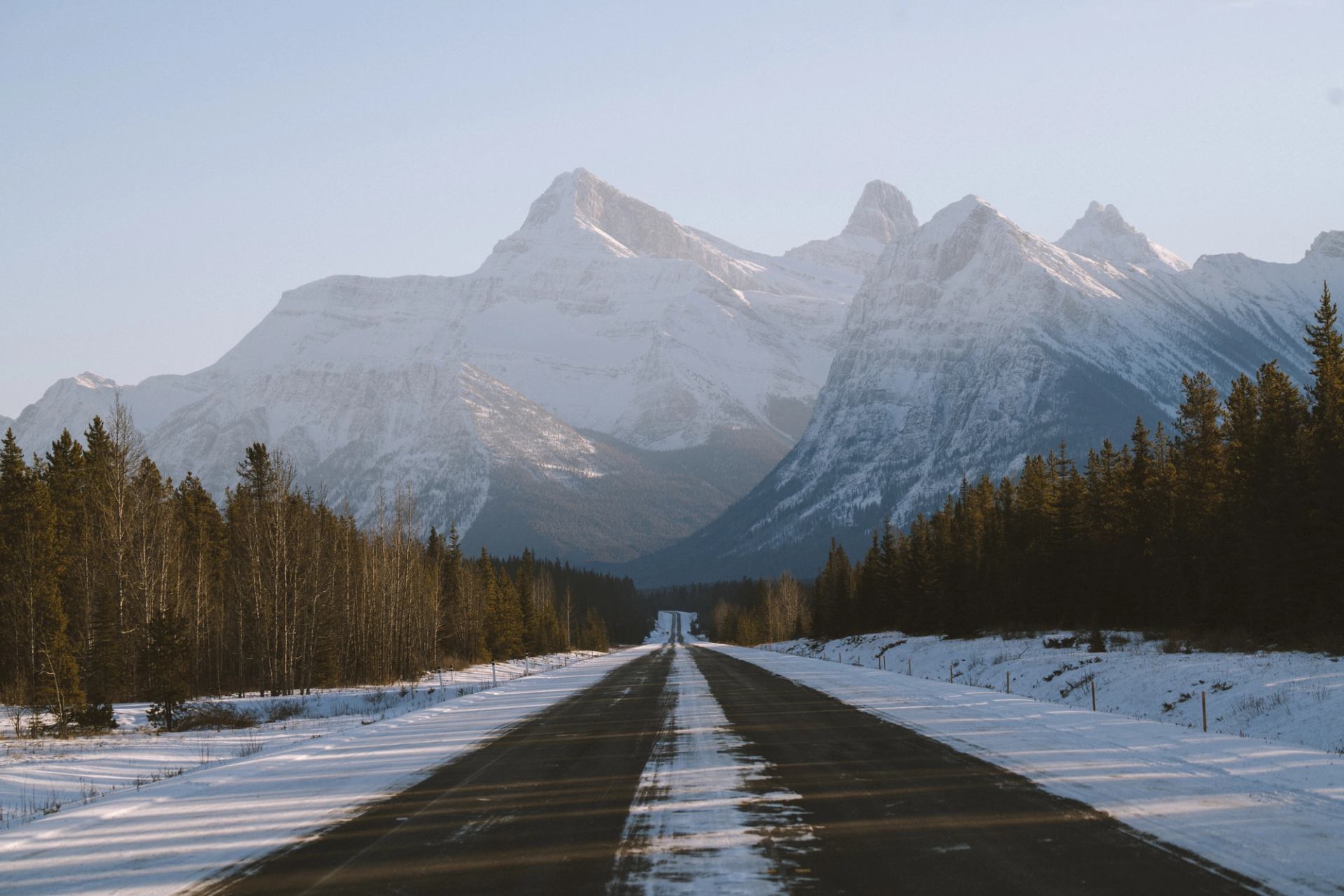 Scenic shot of a country road leading to snow-capped mountain peaks.