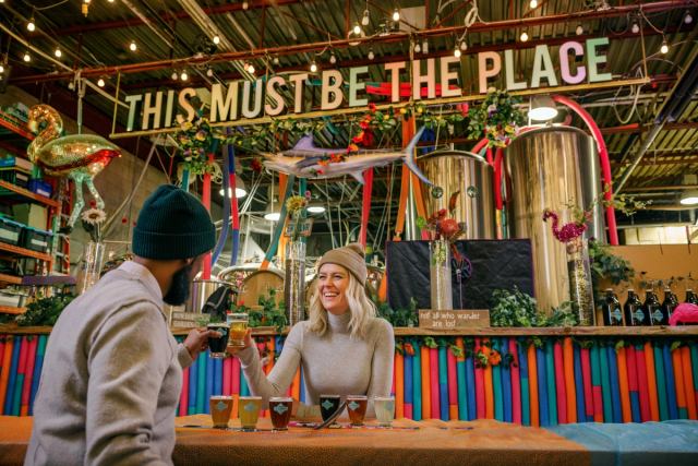 A couple cheersing while enjoying a flight of beer at the colourfully decorated Cold Garden in Calgary