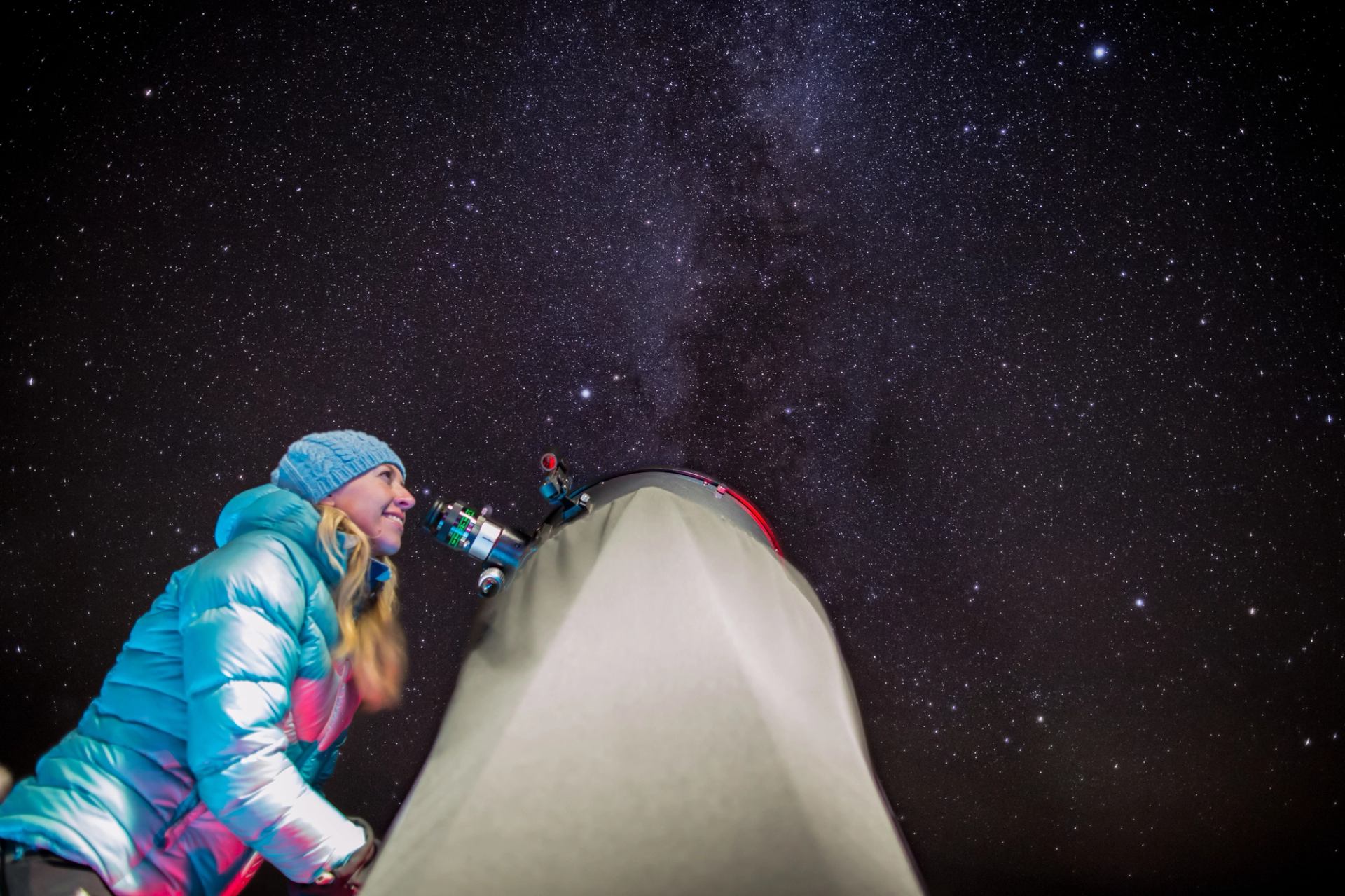 Woman looking at the stars through a telescope