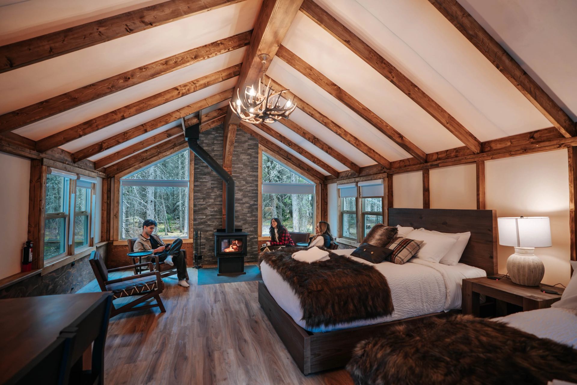 Travellers relax in a luxe glamping tent at Sundance by Basecamp featuring wood floors, 2 beds, premium linens and comfy seating.