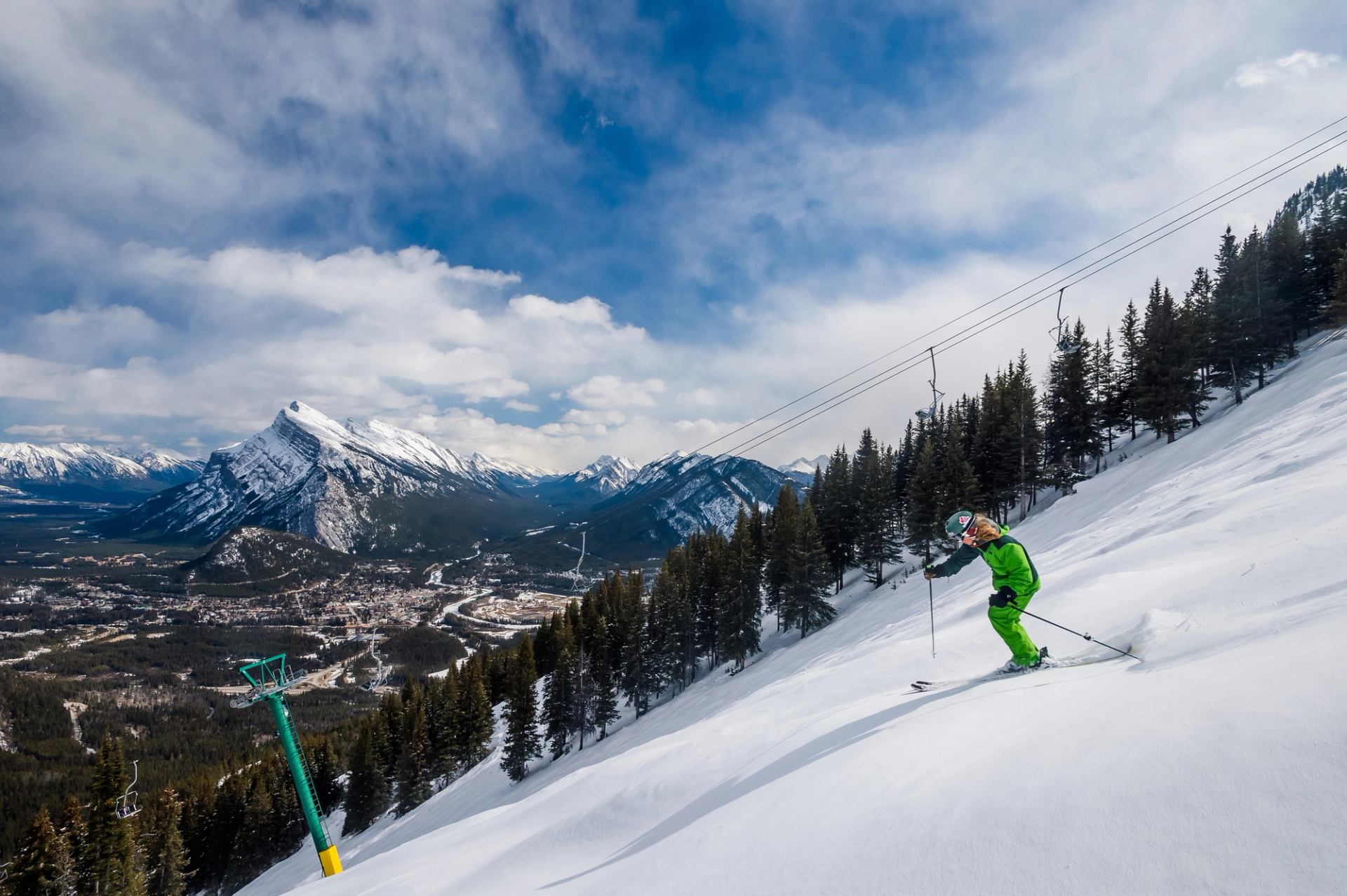 Skier under the chairlift, mountains in the background, skiing at Mount Norquay in Banff National Park