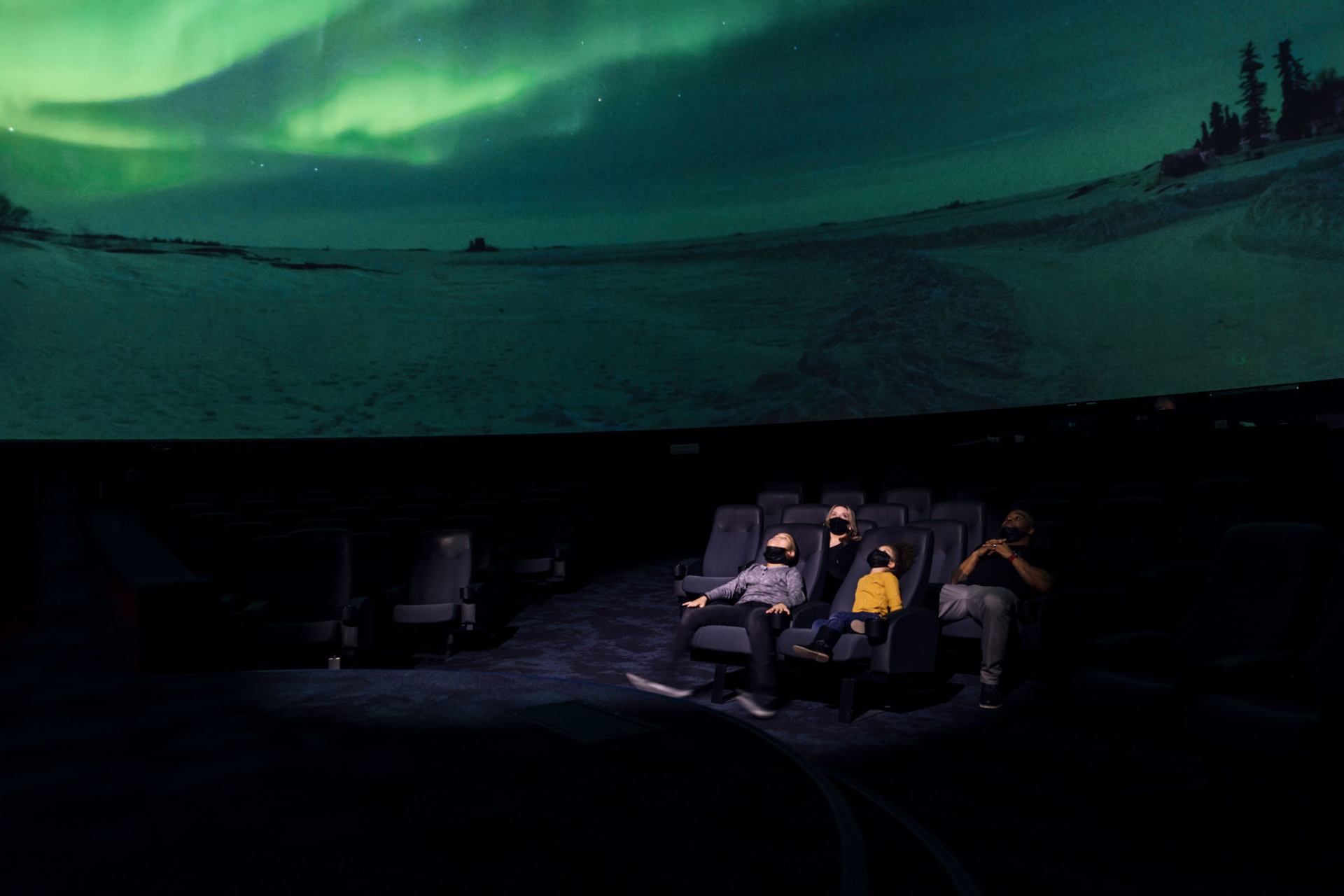 Science centre visitors lay back and watch the aurora borealis on a big screen above.