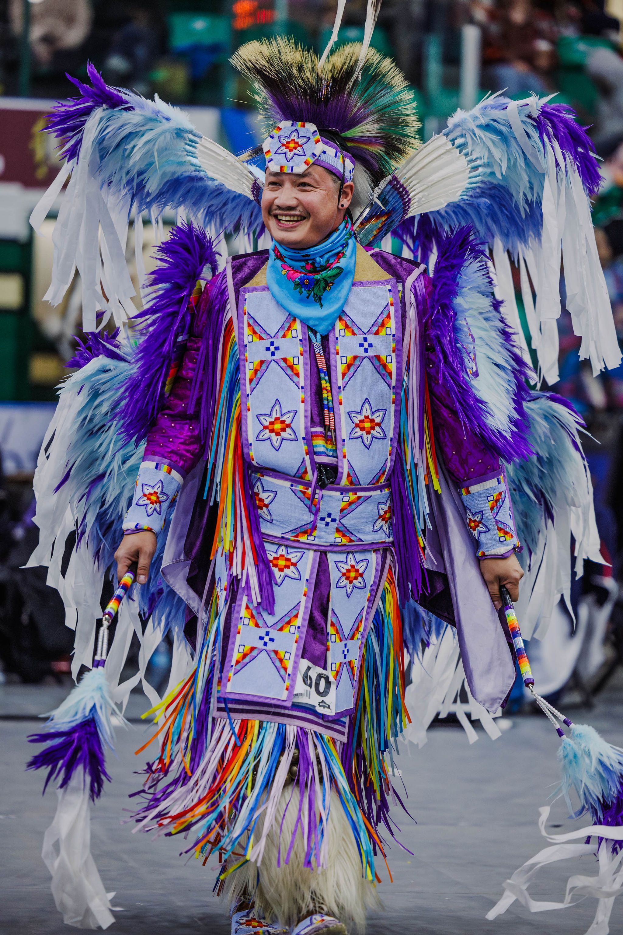 A young powwow dancer in colourful regalia, featuring lime green, bright yellow and other colours, performs at a powwow.