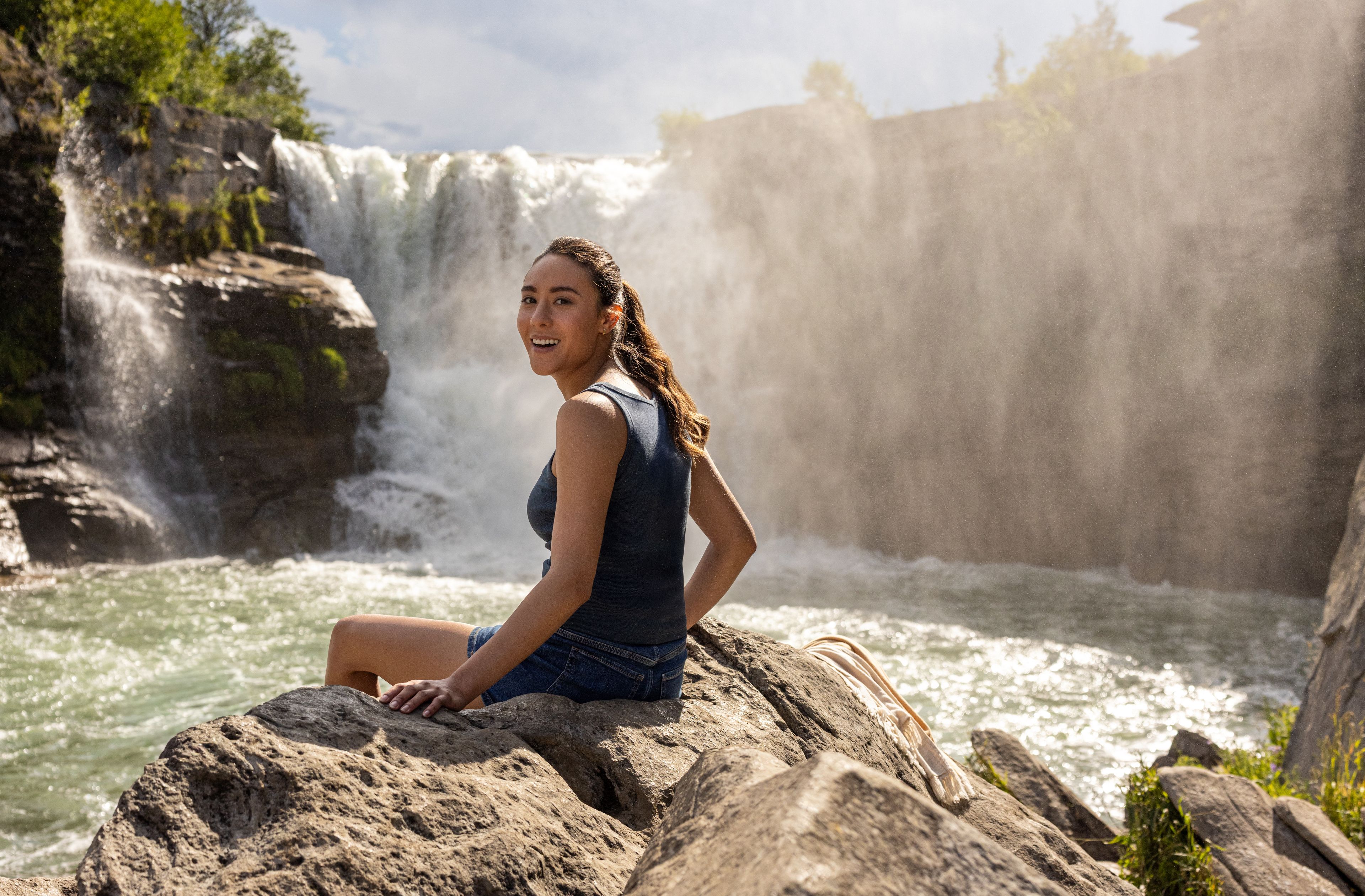 A woman smiles while sitting on a rock near Lundbreck Falls.