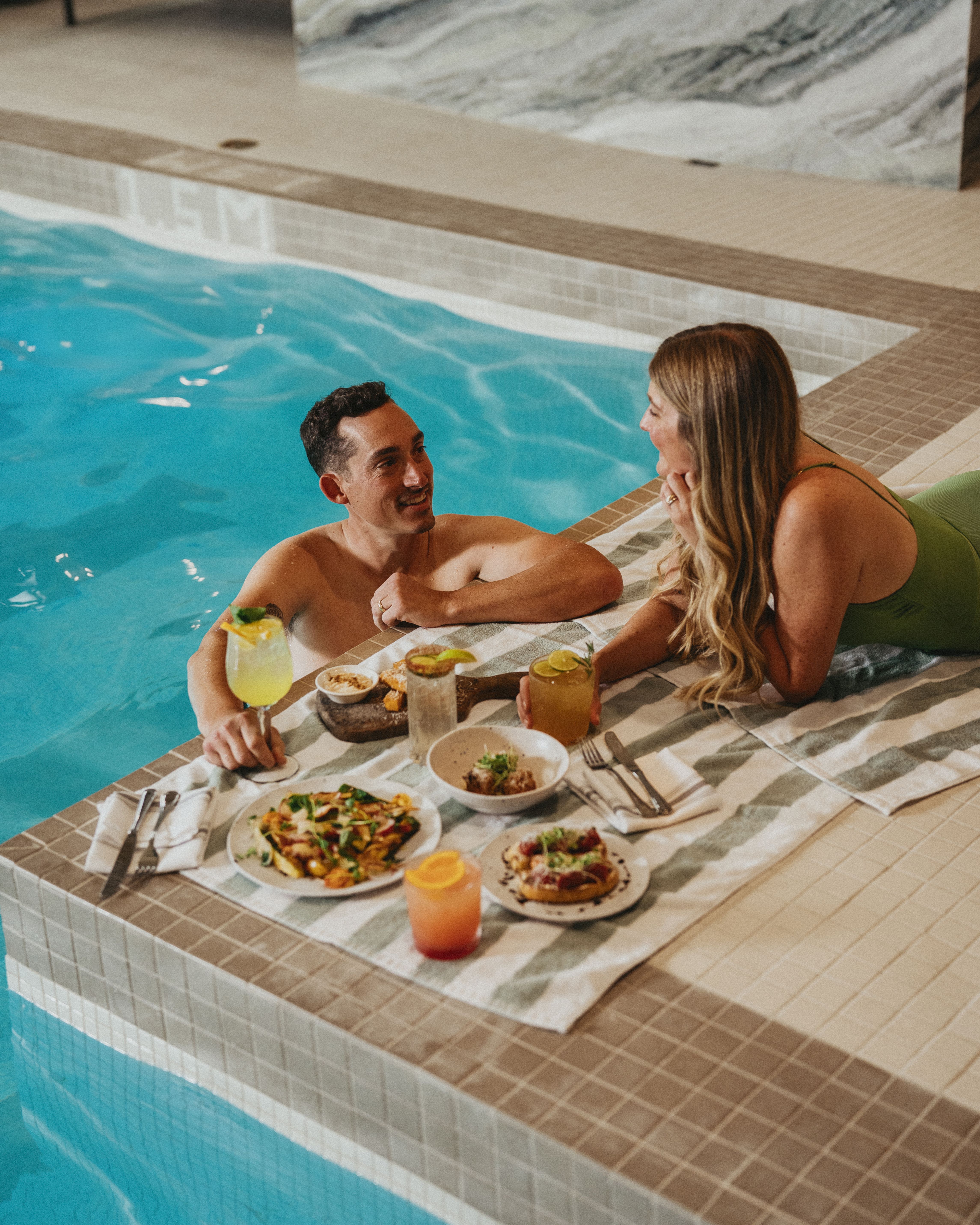 Two people eat and soak poolside at The Kenrick Hotel.